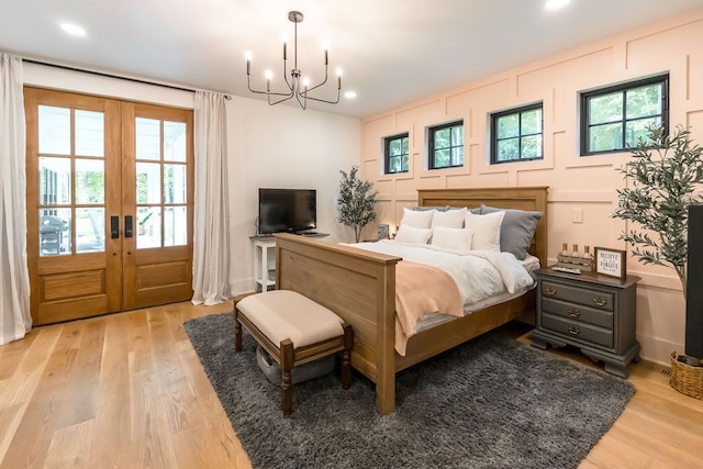 bedroom with access to exterior, a chandelier, french doors, and light hardwood / wood-style floors