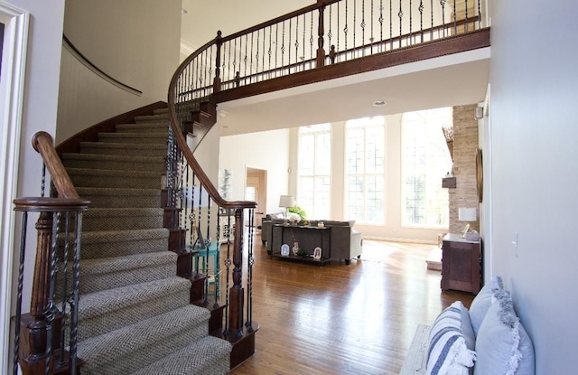 stairs featuring a towering ceiling and hardwood / wood-style flooring