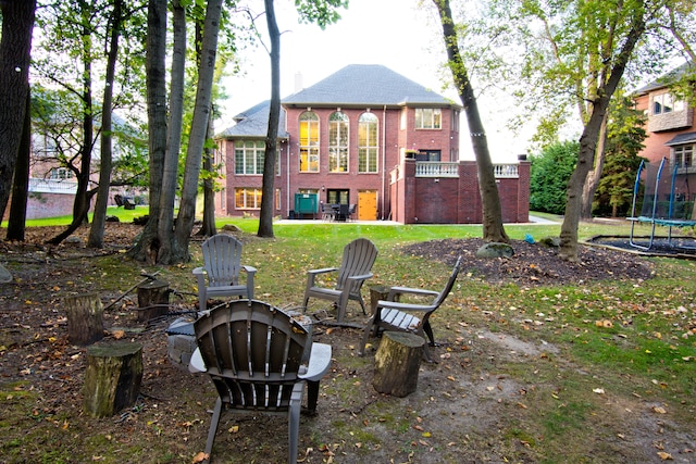 rear view of property with a trampoline and an outdoor fire pit