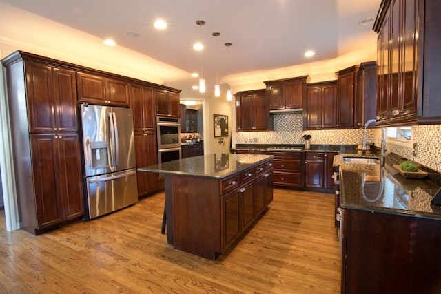 kitchen featuring sink, hanging light fixtures, light hardwood / wood-style flooring, a kitchen island, and appliances with stainless steel finishes