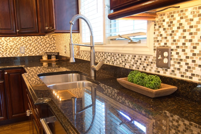 kitchen with backsplash, dark stone countertops, sink, and dark hardwood / wood-style floors