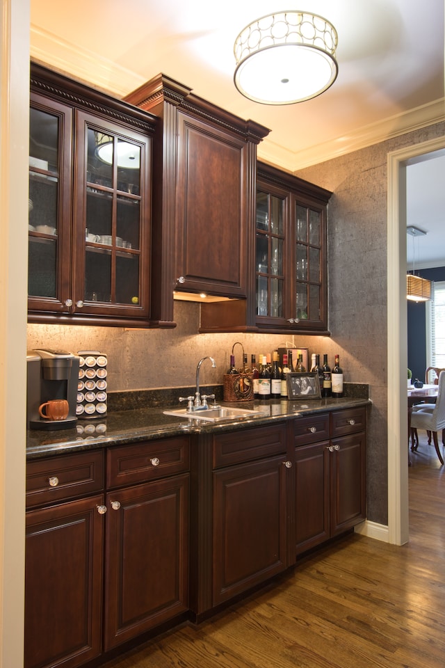 bar featuring dark brown cabinets, ornamental molding, dark hardwood / wood-style floors, and sink