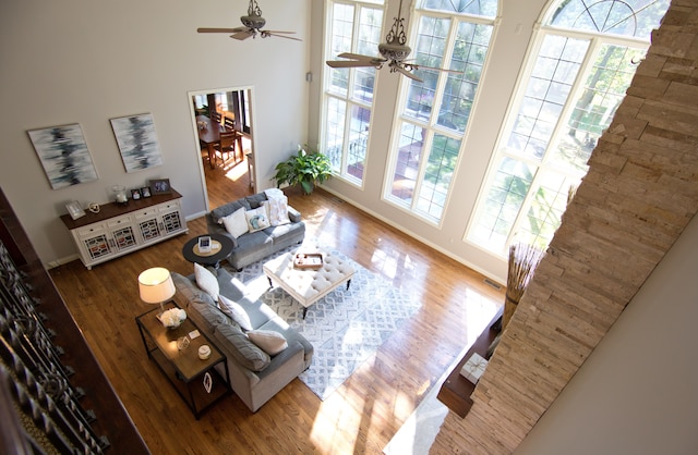 living room featuring a wealth of natural light, ceiling fan, a high ceiling, and light wood-type flooring