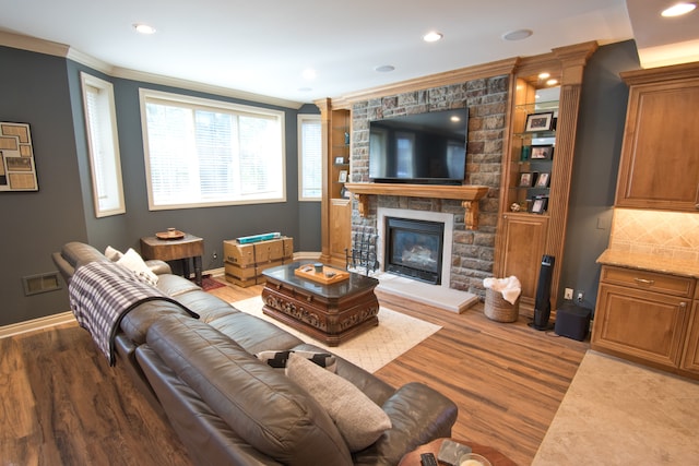 living room with wood-type flooring, ornamental molding, and a fireplace