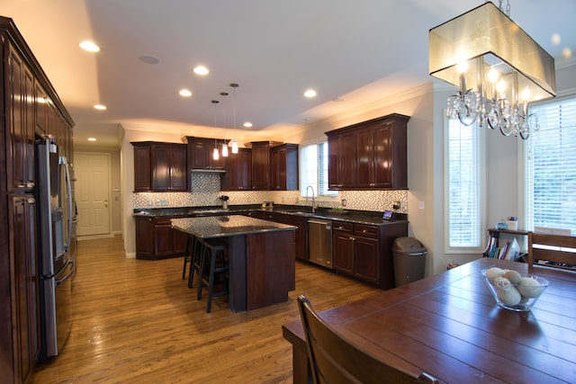 kitchen featuring backsplash, a kitchen island, hanging light fixtures, and ornamental molding