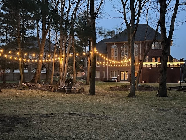 yard at dusk featuring a trampoline