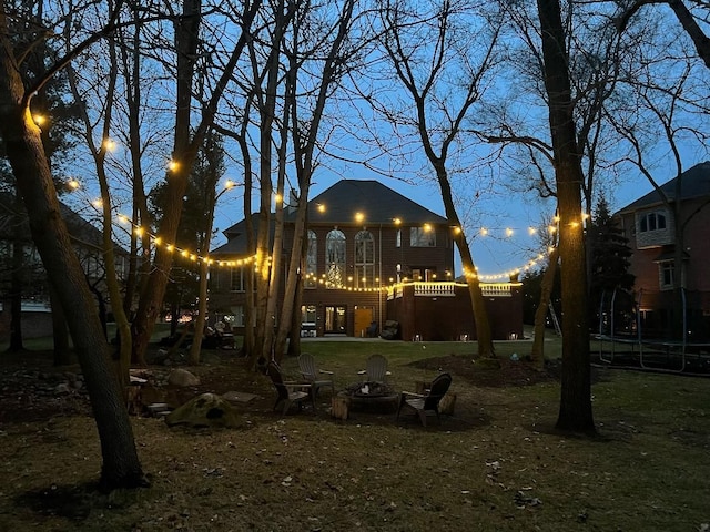 rear view of house featuring an outdoor fire pit, a balcony, and a trampoline