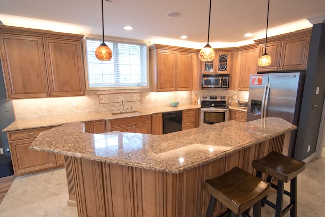 kitchen with pendant lighting, sink, a breakfast bar area, and appliances with stainless steel finishes