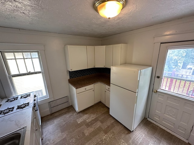 kitchen featuring white cabinets, dark hardwood / wood-style floors, white fridge, and a healthy amount of sunlight