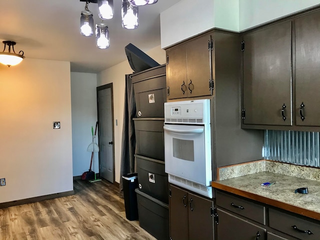 kitchen featuring decorative light fixtures, light hardwood / wood-style floors, and oven