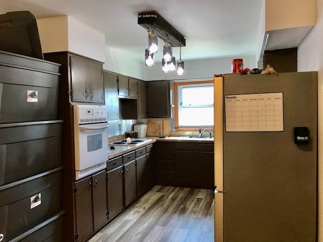 kitchen featuring hanging light fixtures, light hardwood / wood-style flooring, a chandelier, white appliances, and dark brown cabinets