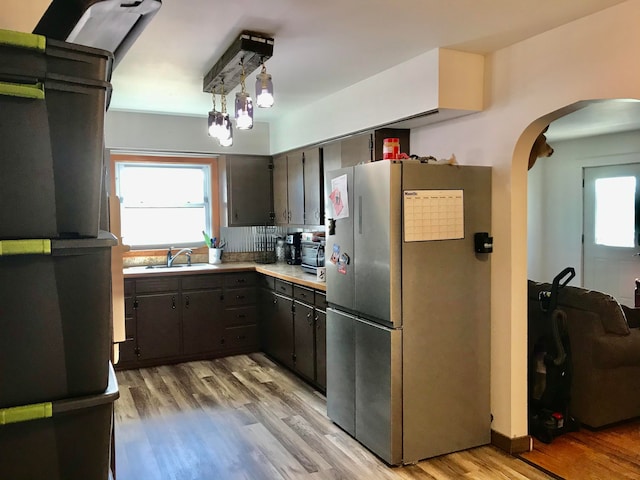 kitchen with appliances with stainless steel finishes, light hardwood / wood-style flooring, pendant lighting, and sink