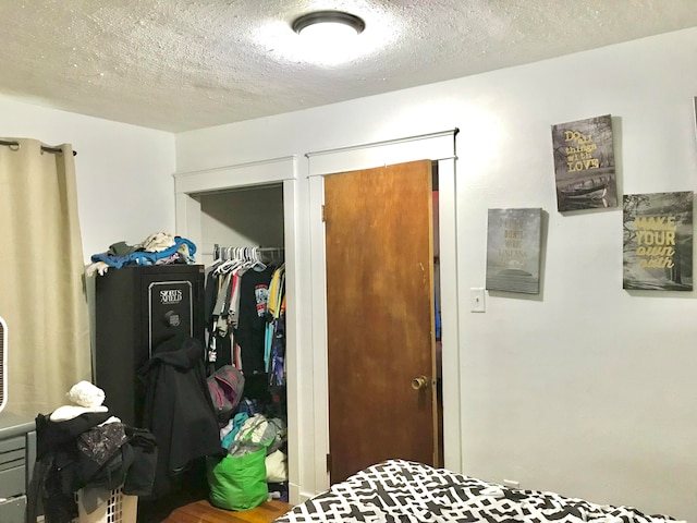 bedroom with hardwood / wood-style floors, a textured ceiling, and a closet