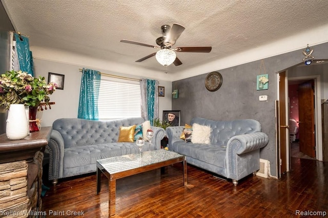 living room with a textured ceiling, ceiling fan, and dark wood-type flooring