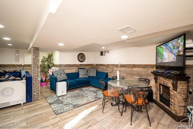 living room with a fireplace, light hardwood / wood-style floors, and tile walls