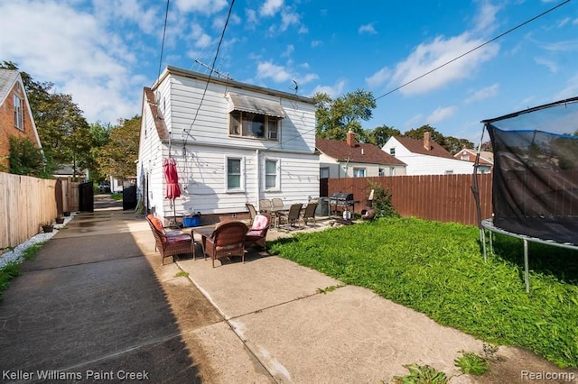 rear view of property with a patio and a trampoline