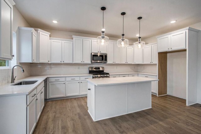 kitchen featuring stainless steel appliances, sink, pendant lighting, dark hardwood / wood-style floors, and white cabinetry