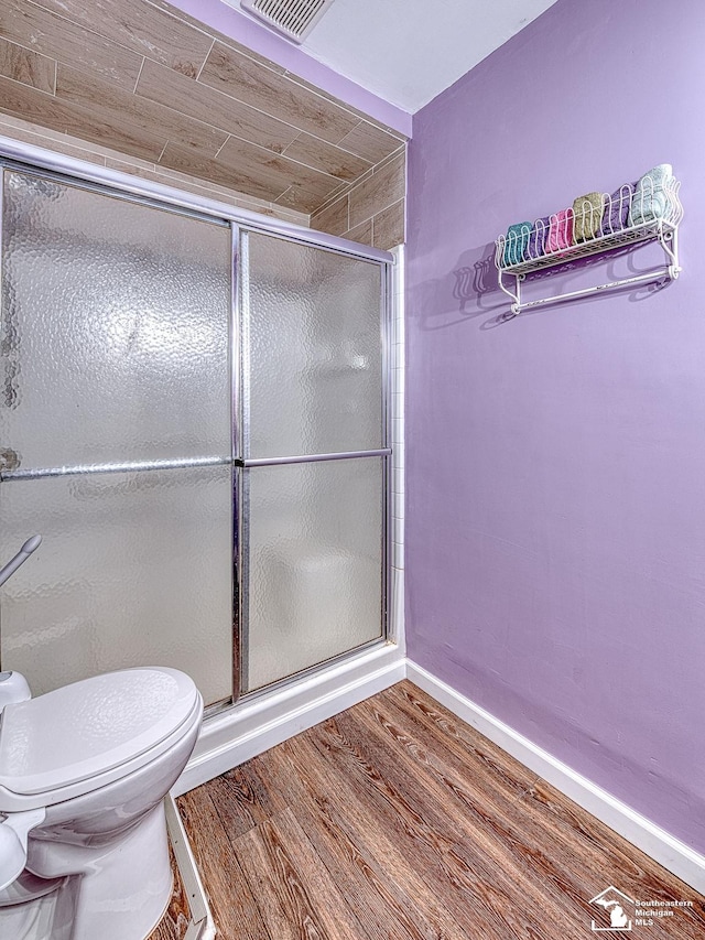 bathroom featuring hardwood / wood-style floors, an enclosed shower, and toilet