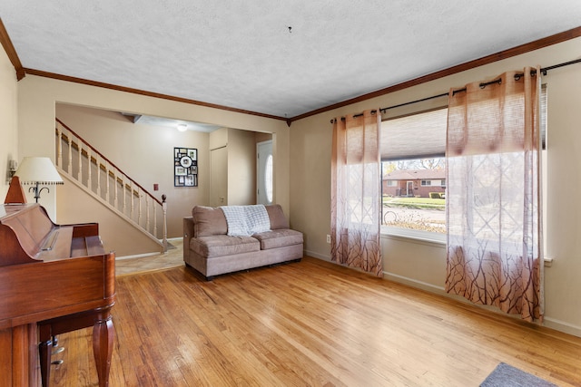 living room with crown molding, a textured ceiling, and light wood-type flooring