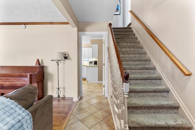 staircase with tile patterned flooring and ornamental molding