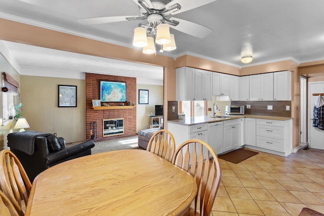 kitchen featuring a fireplace, ceiling fan, sink, dishwasher, and white cabinets