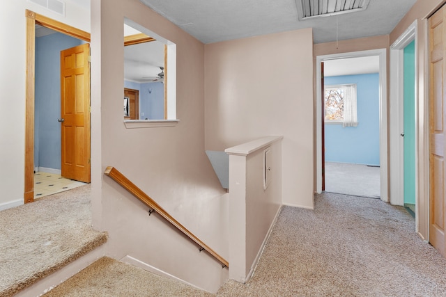 corridor featuring a textured ceiling and light carpet