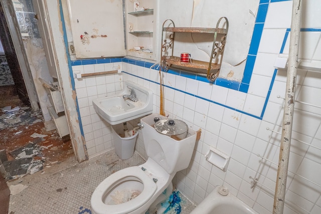 bathroom featuring a tub to relax in, toilet, tile walls, and sink