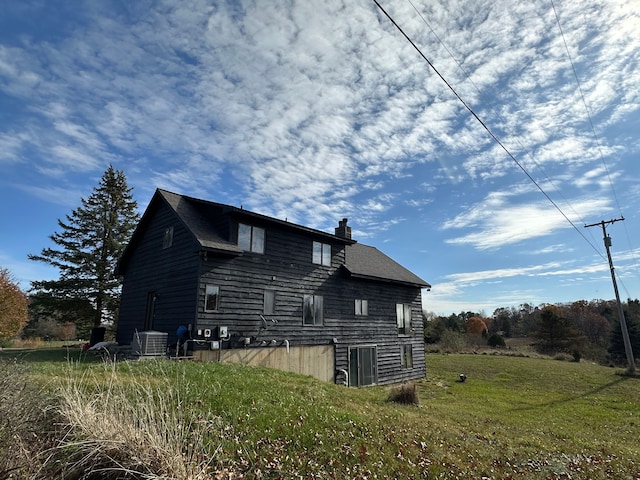 view of side of home featuring a yard and central AC unit