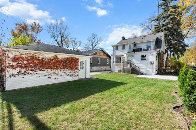 rear view of house with a lawn and a balcony