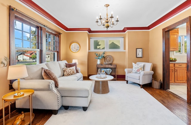 living room with crown molding, wood-type flooring, and an inviting chandelier