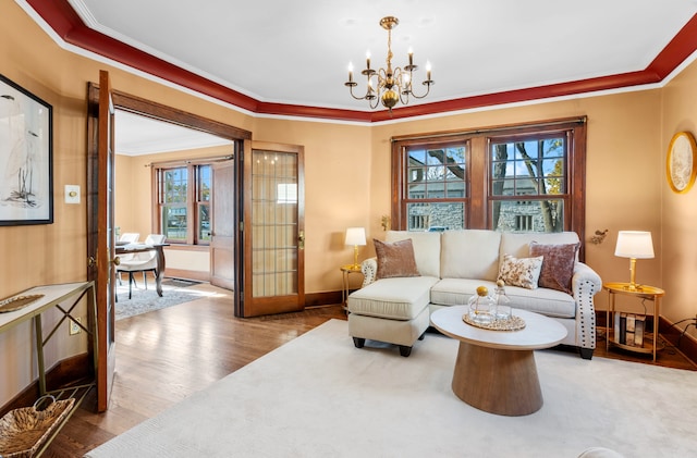 living room with hardwood / wood-style flooring, a wealth of natural light, ornamental molding, and a notable chandelier