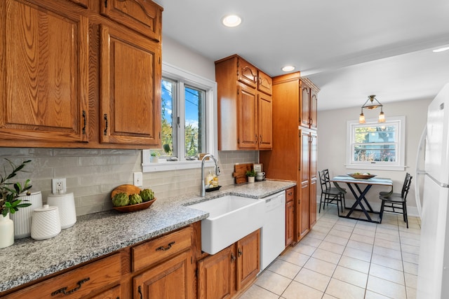 kitchen with light stone countertops, sink, white appliances, decorative backsplash, and light tile patterned flooring