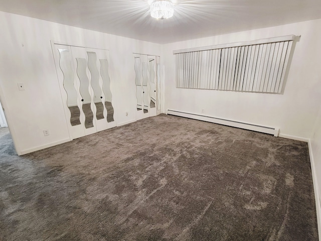 empty room with dark carpet and a baseboard heating unit