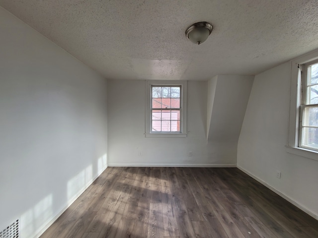 empty room featuring a wealth of natural light, dark hardwood / wood-style floors, and a textured ceiling