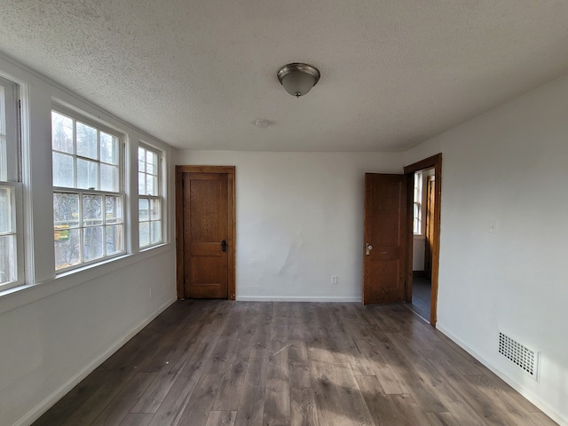 unfurnished room featuring dark hardwood / wood-style flooring and a textured ceiling