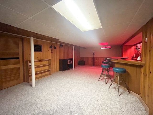 bar featuring carpet flooring, a paneled ceiling, and wooden walls