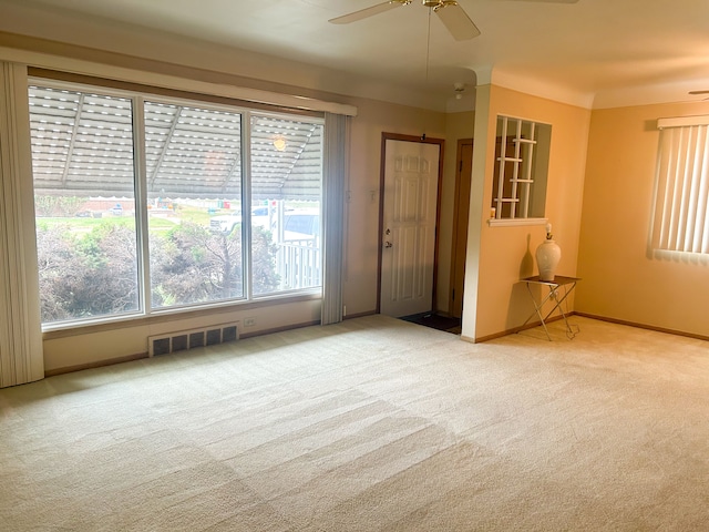 carpeted spare room with ceiling fan and a wealth of natural light