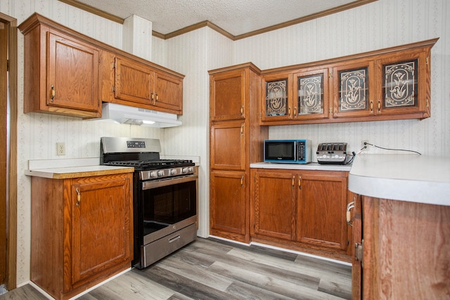 kitchen with gas stove, light hardwood / wood-style floors, a textured ceiling, and ornamental molding