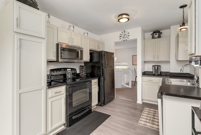 kitchen with black appliances, sink, decorative light fixtures, light hardwood / wood-style floors, and white cabinetry