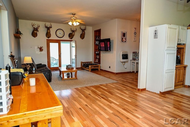 living room with heating unit, ceiling fan, and light hardwood / wood-style flooring