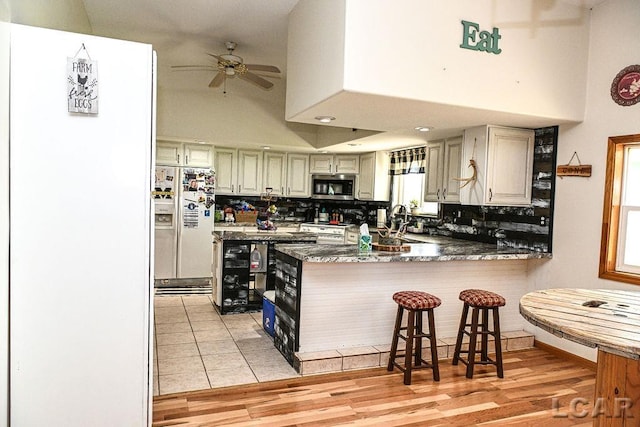 kitchen with ceiling fan, light hardwood / wood-style floors, a high ceiling, and appliances with stainless steel finishes