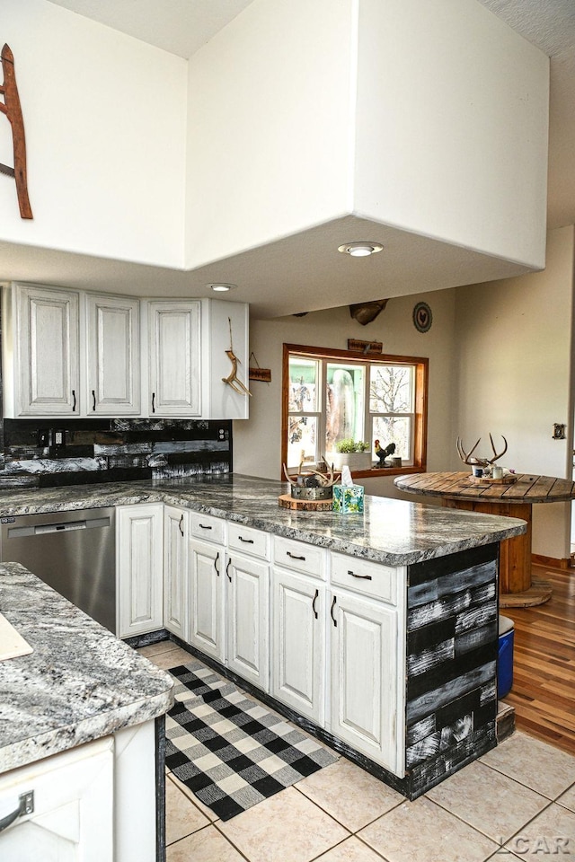 kitchen featuring dishwasher, light tile patterned floors, white cabinetry, and dark stone countertops