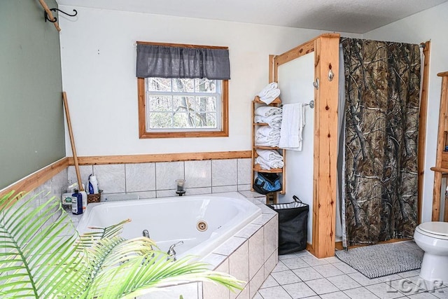 bathroom featuring tile patterned floors, tiled tub, and toilet