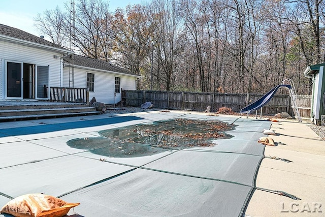 view of swimming pool featuring a wooden deck, a patio, and a water slide