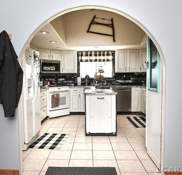 kitchen featuring a raised ceiling, decorative backsplash, light tile patterned floors, and stainless steel appliances