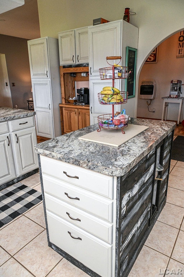 kitchen with white cabinets, light tile patterned floors, heating unit, and a kitchen island