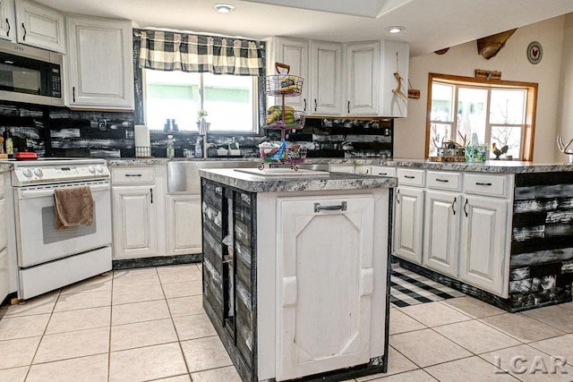 kitchen featuring a center island, white cabinetry, and white stove