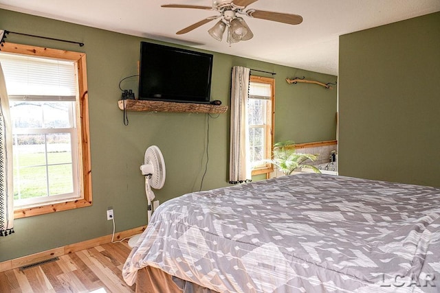 bedroom featuring hardwood / wood-style floors, ceiling fan, and multiple windows