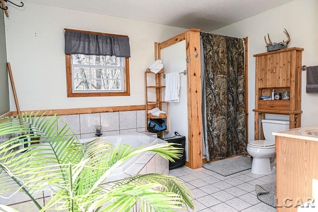 bathroom featuring tile patterned flooring, vanity, toilet, and a tub to relax in