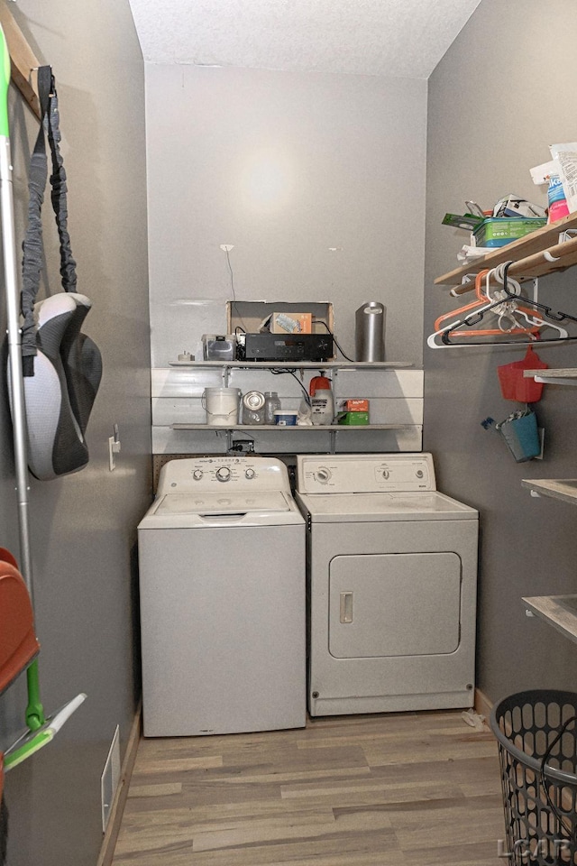 washroom with washer and clothes dryer, wood-type flooring, and a textured ceiling